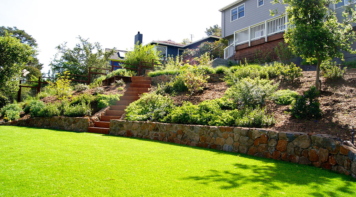 multi-level back yard featuring garden beds, steps and broad lawn.